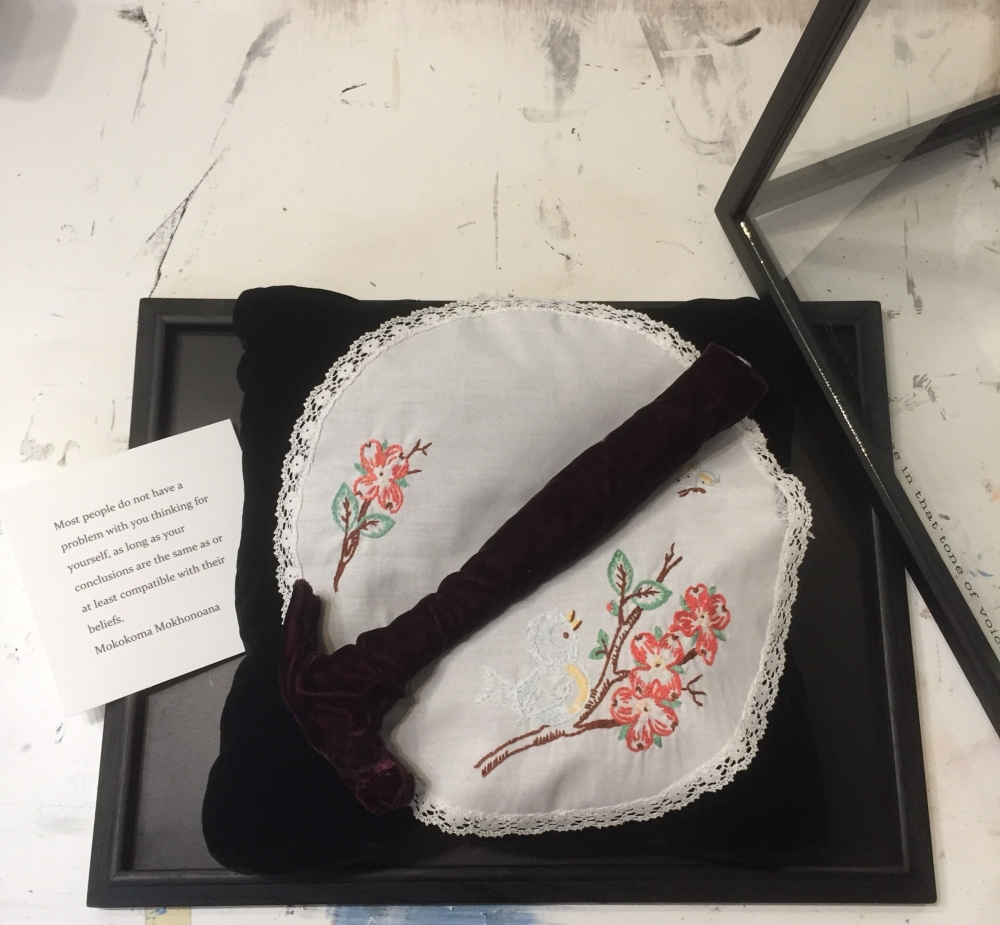 Original mixed media artwork by Judith Ann Miller, with a black velvet pillow, a red velvet hammer, vintage doilie, and a quote from poet Mokokoma Mokhonoana